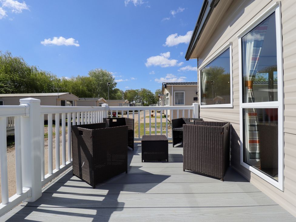 A deck with chairs and a table at 39 Larch View with hot tub Tattershall