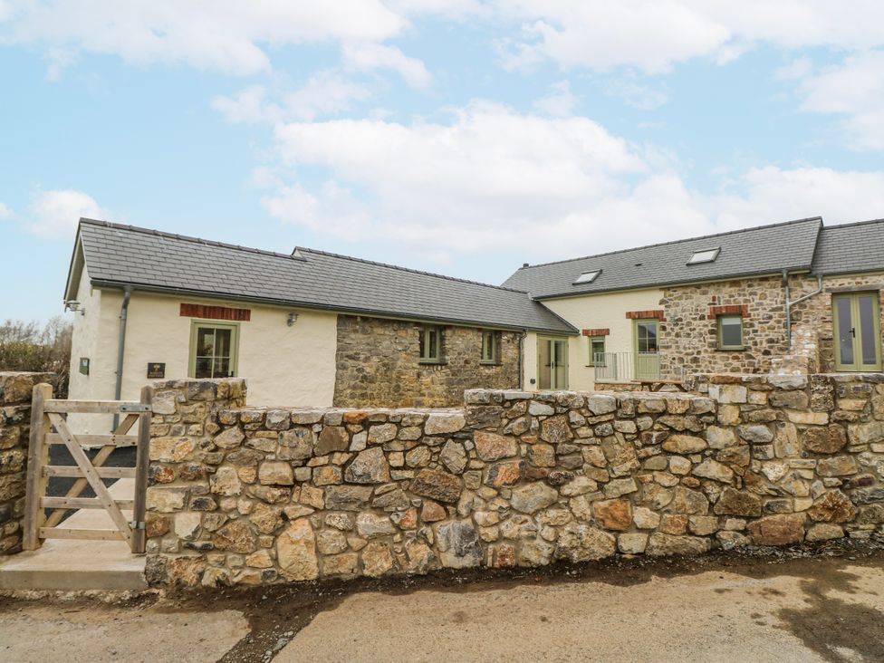 An outdoor view of a stone house and wall at Barley Cottage in Oxwich