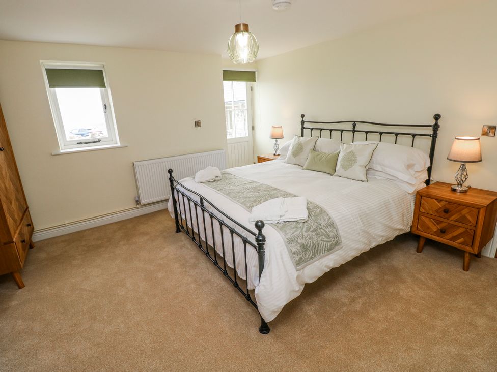 A bedroom with a bed and nightstands at Barley Cottage in Oxwich