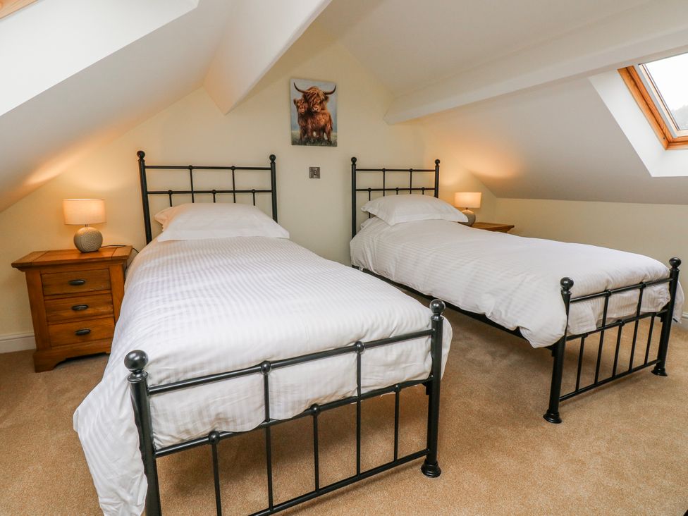 A bedroom with two single beds and a nightstand at Barley Cottage in Oxwich