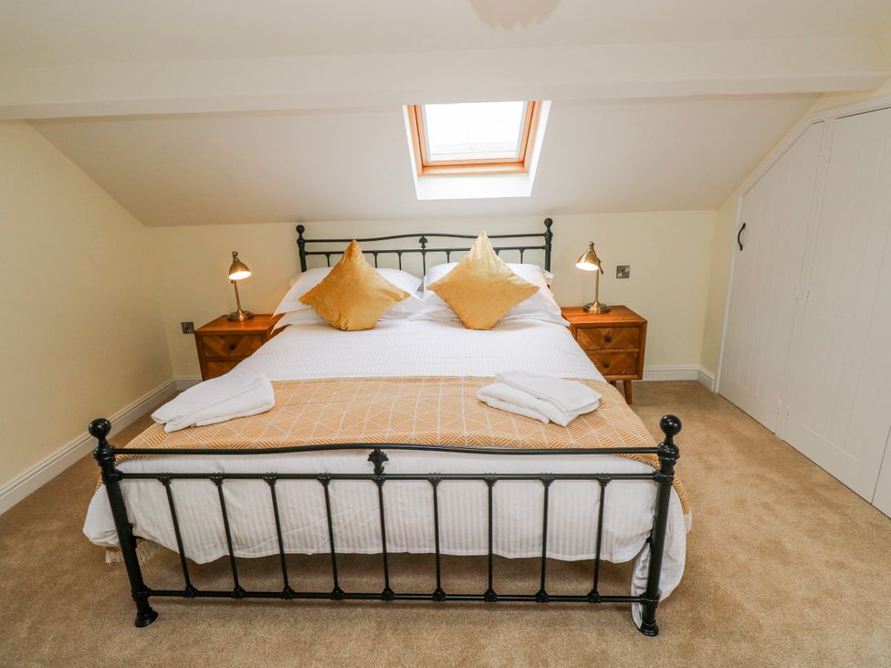 A bedroom with a bed and nightstands at Barley Cottage in Oxwich