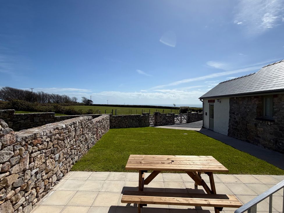An outdoor area with a table and stone walls at Barley Cottage in Oxwich