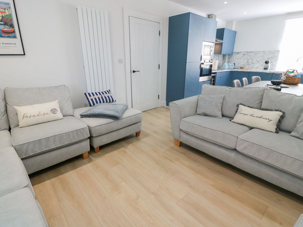 A living room with a sofa and kitchen area at Olea Portpatrick