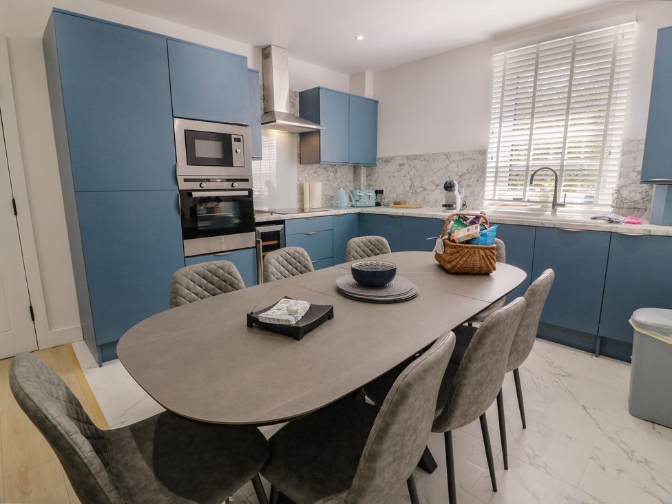A kitchen with blue cabinets and a dining table at Olea in Portpatrick