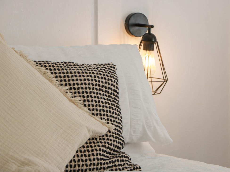 A bed with pillows and a bedside light at Olea Portpatrick