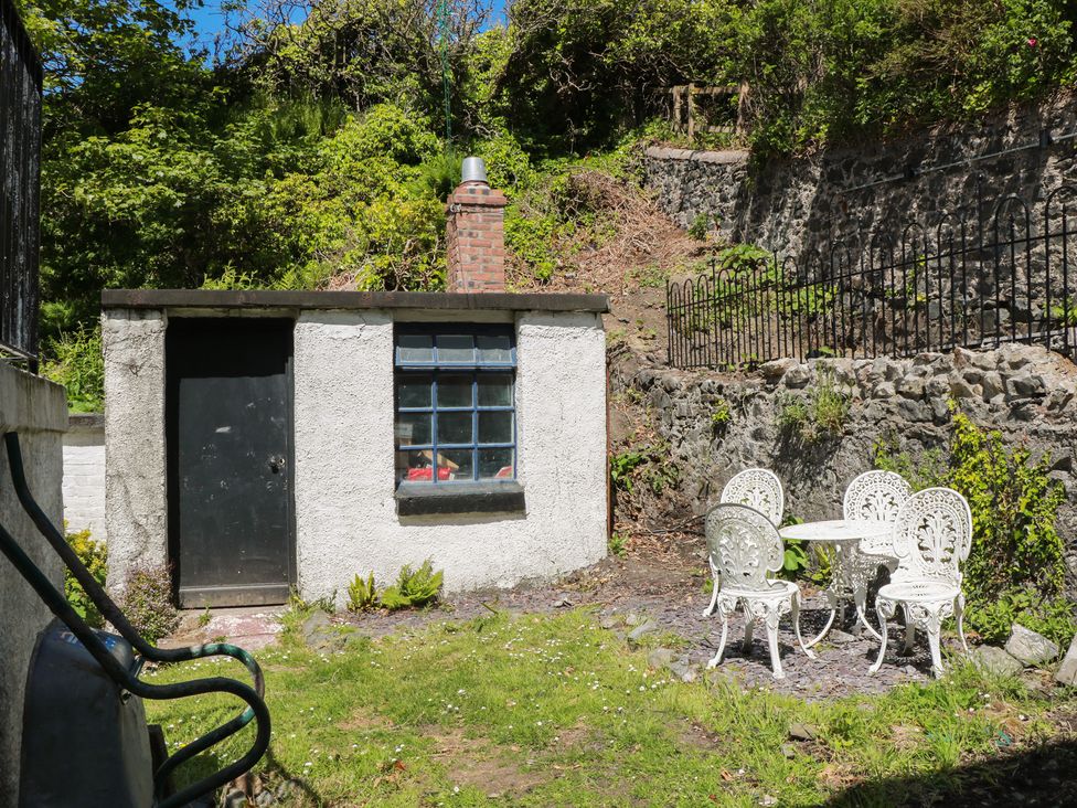 An outdoor area with a small building and white table and chairs at Olea Portpatrick