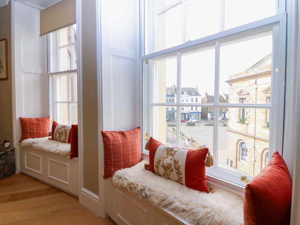A sitting room with window seats and pillows at Woodmarket Apartments in Kelso