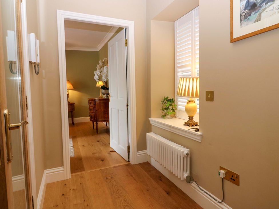 A hallway with a plant, lamp and console table at Woodmarket Apartments in Kelso