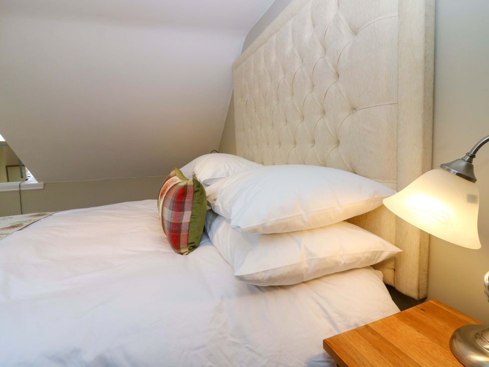 A bed with pillows and a lamp on a nightstand at Woodmarket Apartments in Kelso