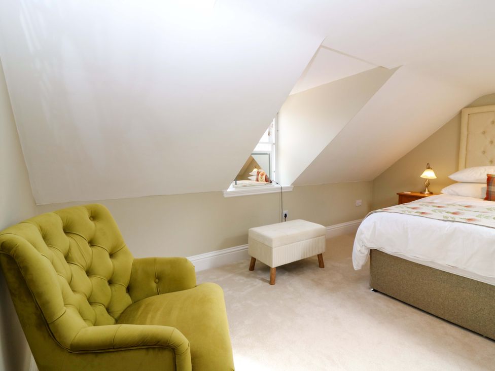 A bedroom with a bed and an armchair at Woodmarket Apartments in Kelso