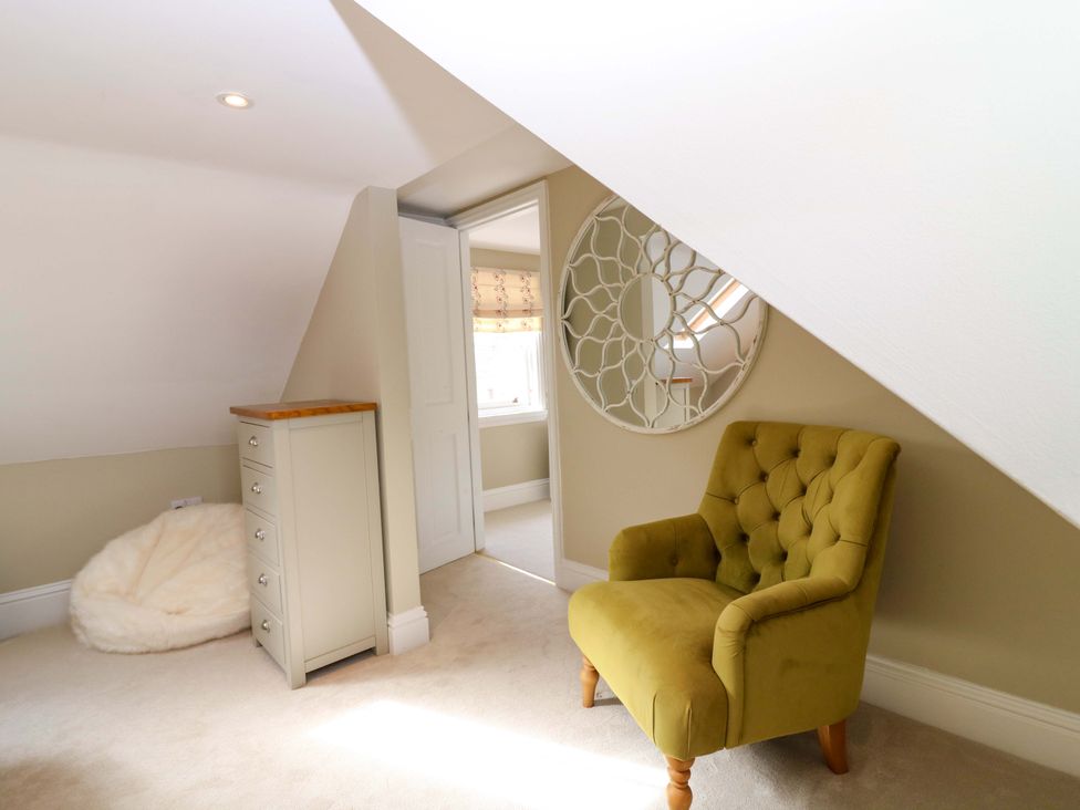 An attic room with an armchair and a mirror at Woodmarket Apartments in Kelso