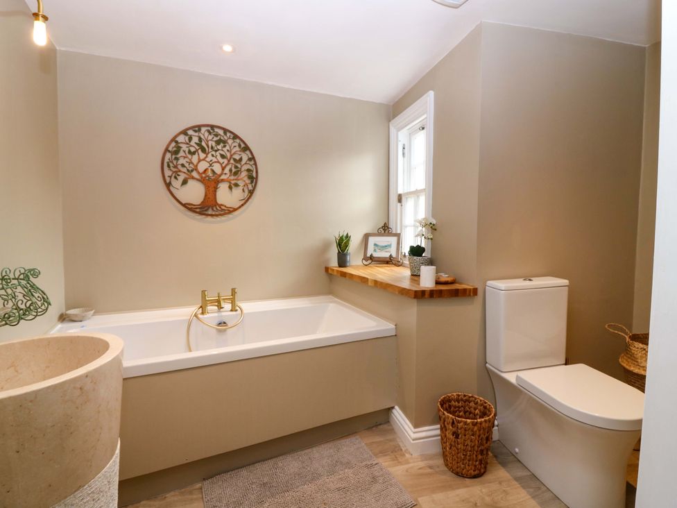 A bathroom with a bathtub, toilet and decor at Woodmarket Apartments in Kelso