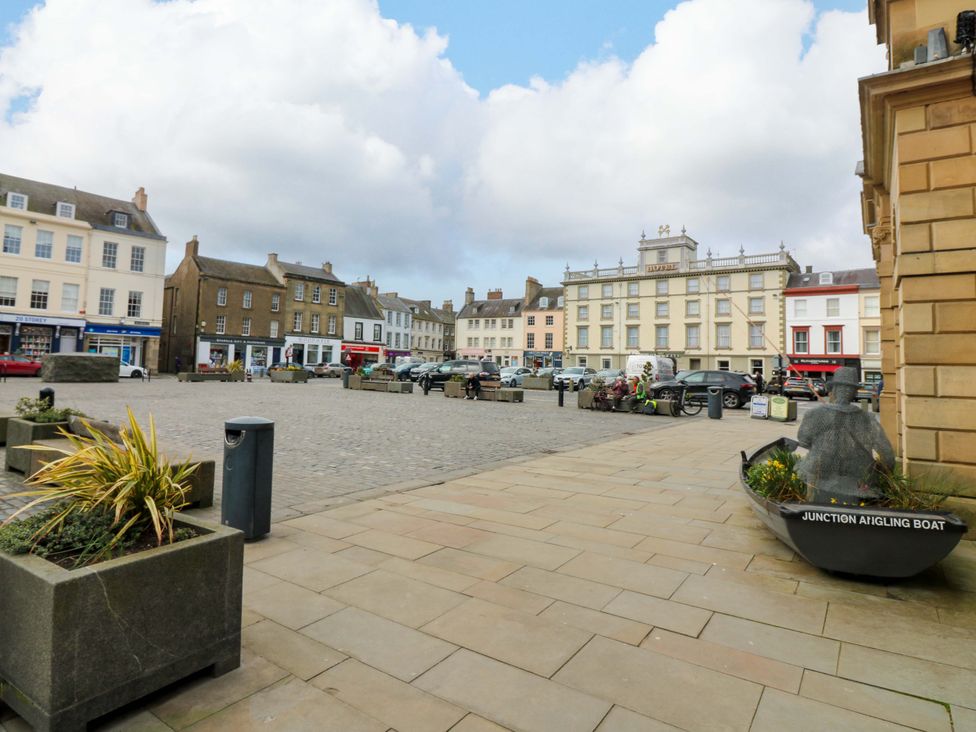 An outdoor square with shops and cars at Woodmarket Apartments in Kelso