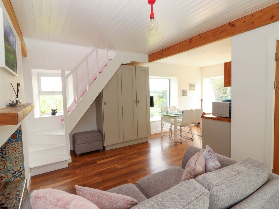 A living room with a staircase and dining area at Artist’s Cottage Cashel, County Tipperary
