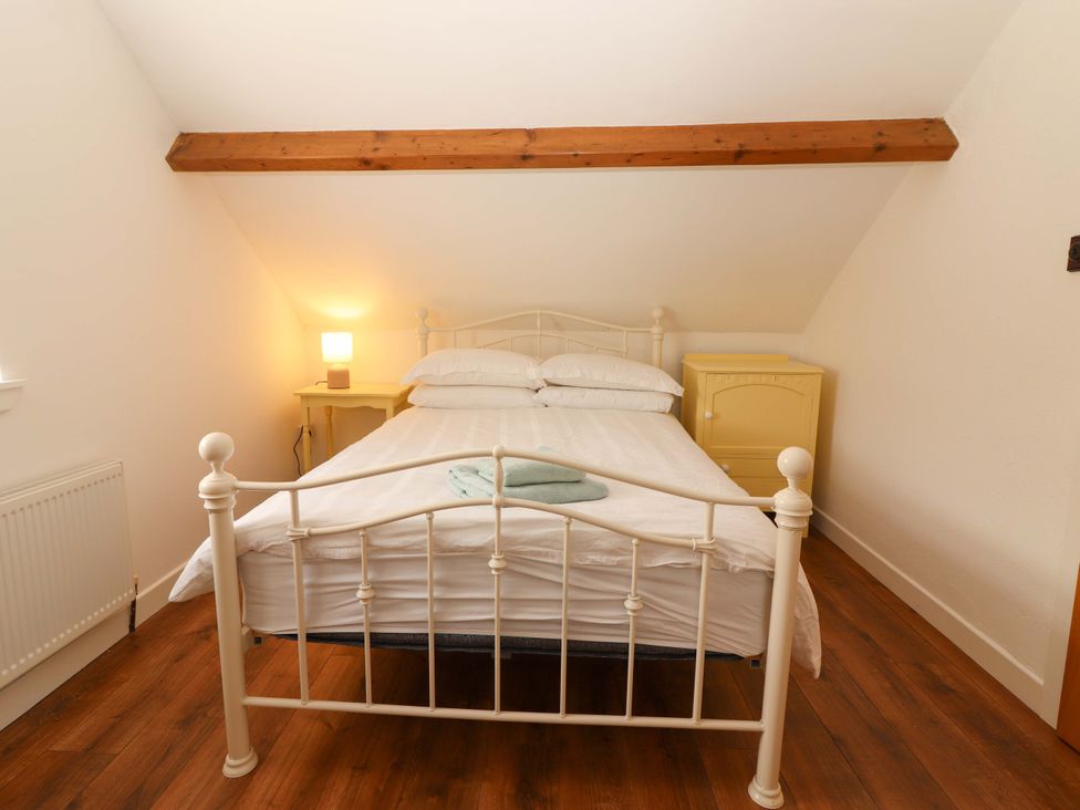 A bedroom with a bed and a yellow dresser at Artist’s Cottage, Cashel, County Tipperary