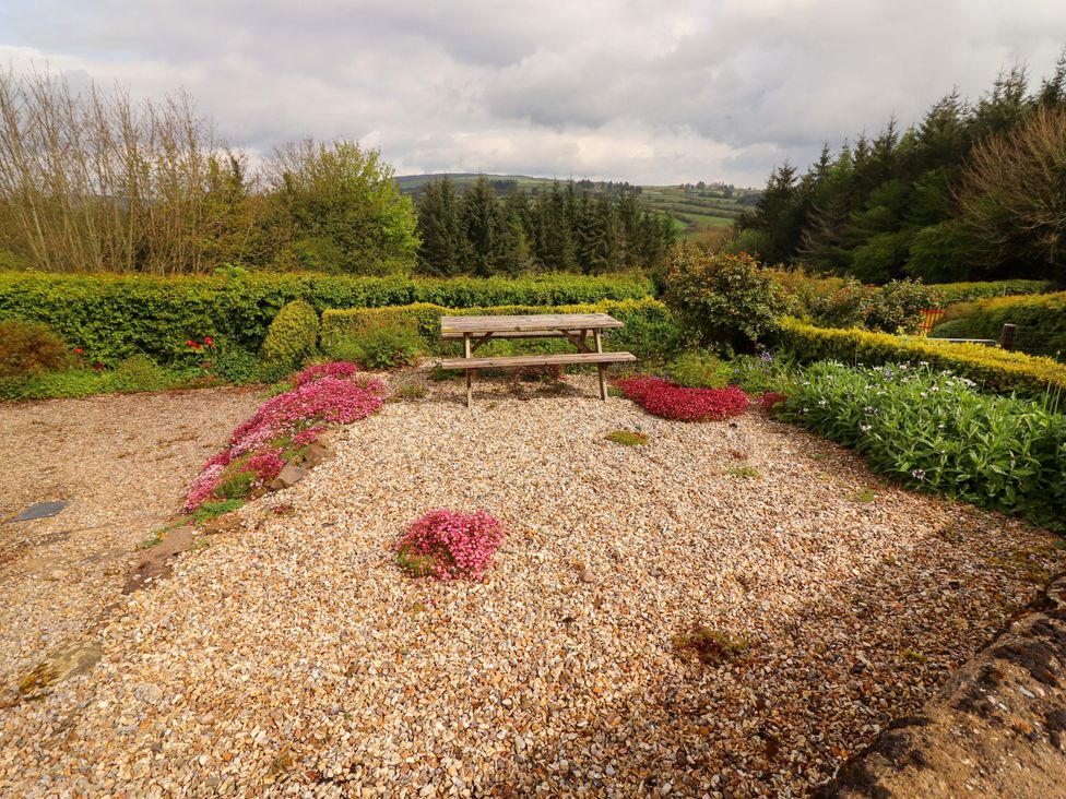 A garden area with a picnic table surrounded by gravel and flowers at Artist’s Cottage in Cashel, County Tipperary