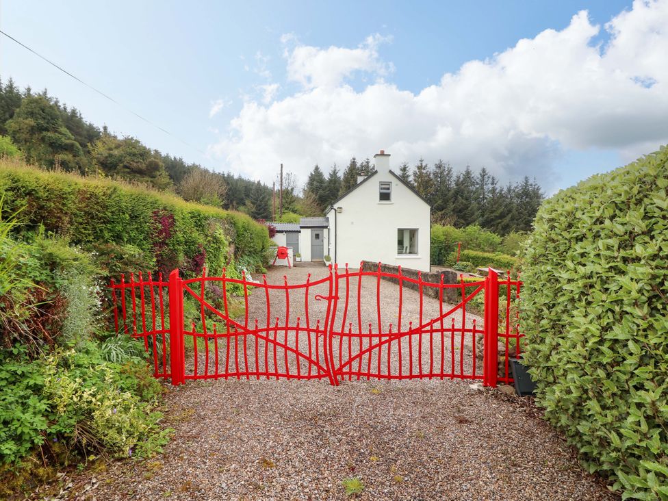 An entrance with a red gate leading to a house at Artist’s Cottage in Cashel, County Tipperary