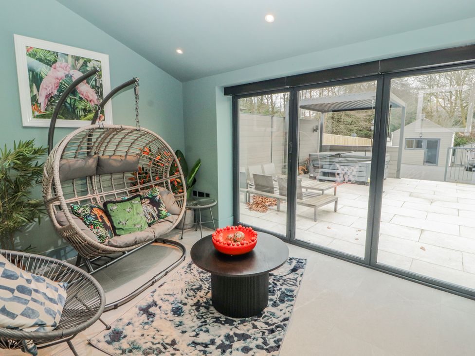 A conservatory with a hanging chair and coffee table at Bounty Boutique on the Lakes in Bowness-On-Windermere