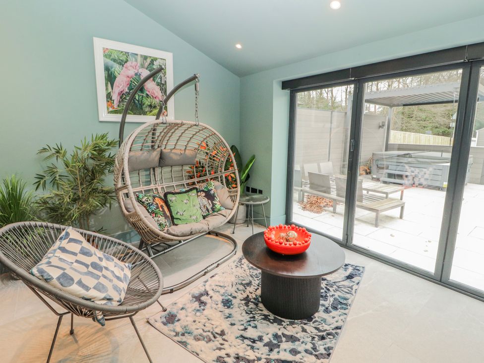 A conservatory with a hanging chair and table at Bounty Boutique on the Lakes in Bowness-On-Windermere