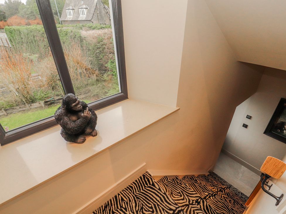 A staircase with a gorilla statue on the windowsill at Bounty Boutique on the Lakes Bowness-On-Windermere