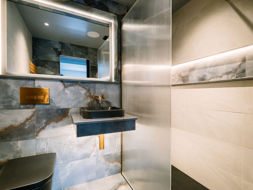 A bathroom with a sink, mirror, and shower at Bounty Boutique on the Lakes in Bowness-On-Windermere