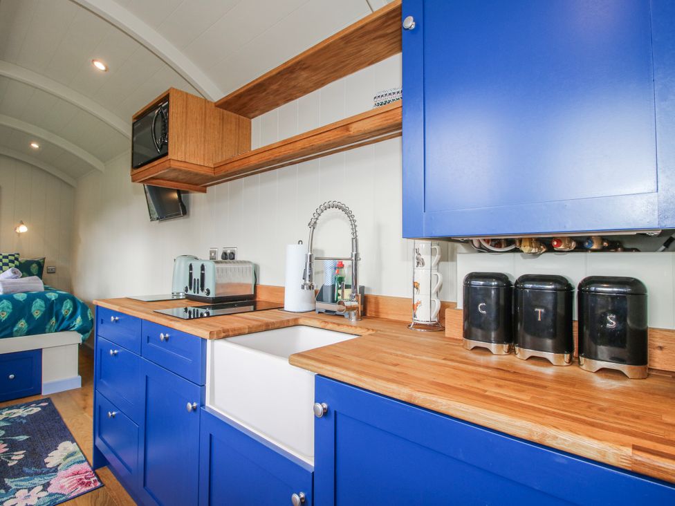 A kitchen with blue cabinets and wooden counter at Skye in Clee Hill
