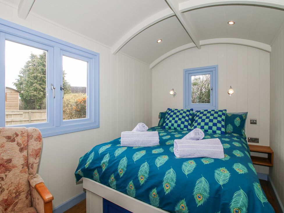 A bedroom with a bed in blue theme and a chair at Skye in Clee Hill