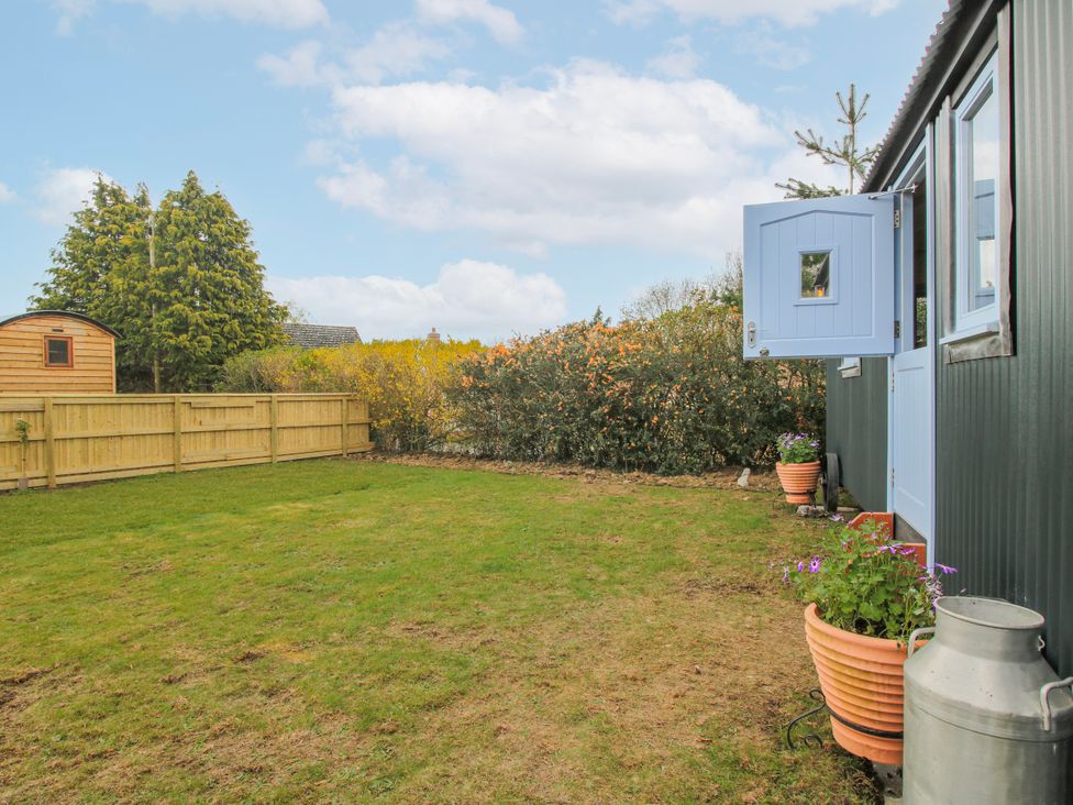 A garden with a wooden shed and planters at Skye in Clee Hill