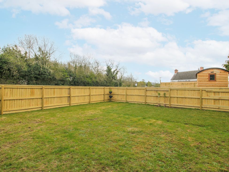 An outdoor garden with a grass area and wooden fence at Skye in Clee Hill