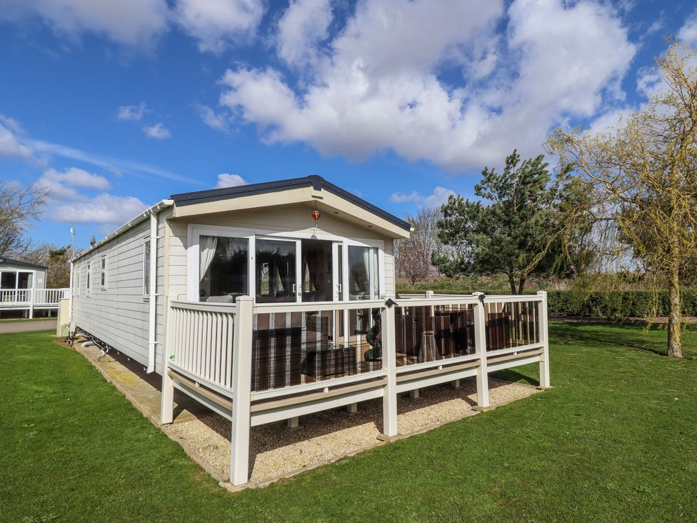 A house with a deck and railing surrounded by grass at 13 The Lakes Mablethorpe