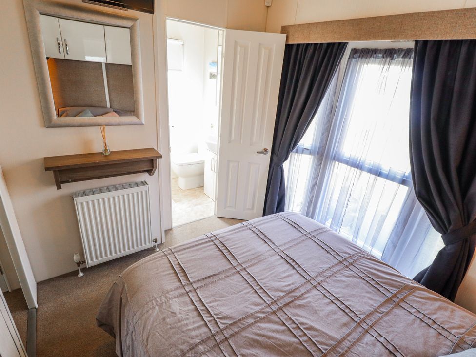 A bedroom with a bed and a door to the bathroom at 13 The Lakes in Mablethorpe