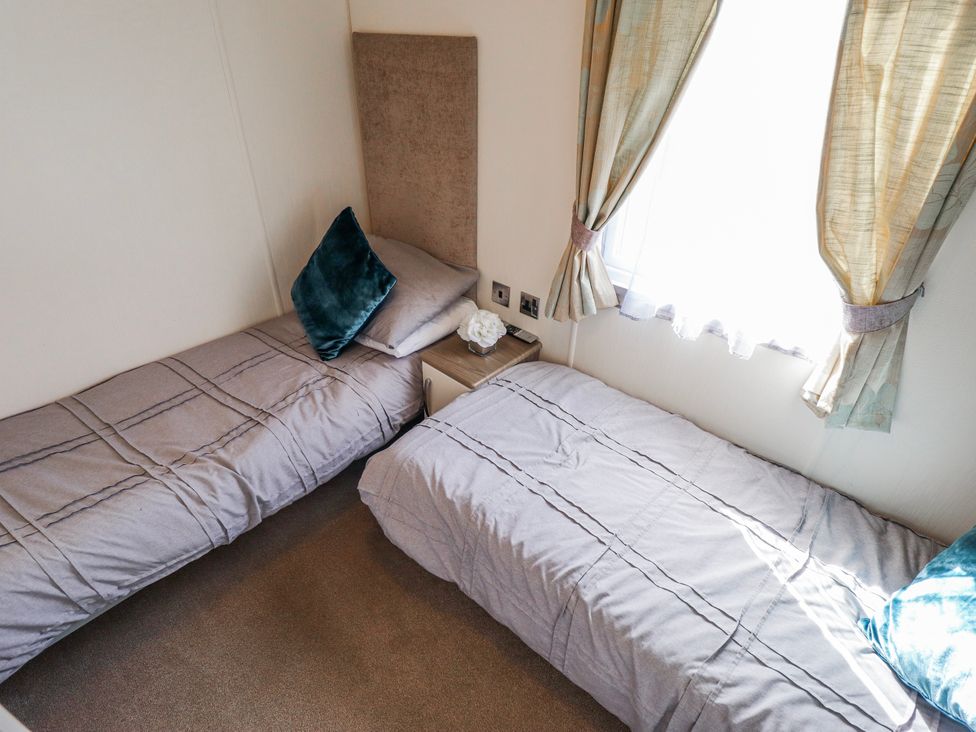 A bedroom with two beds and a window at 13 The Lakes in Mablethorpe