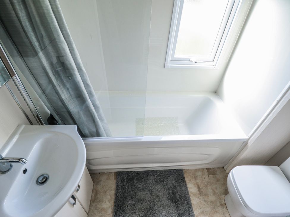 A bathroom with a bathtub, sink and toilet at 13 The Lakes in Mablethorpe