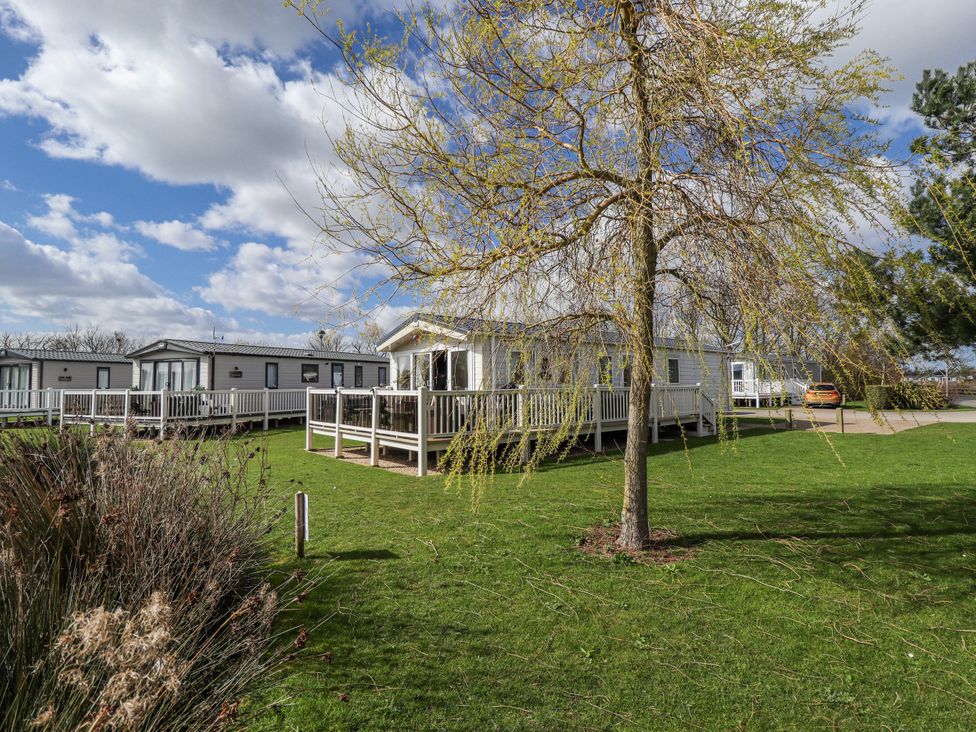 A mobile home with a deck and tree in the outdoor area at 13 The Lakes in Mablethorpe