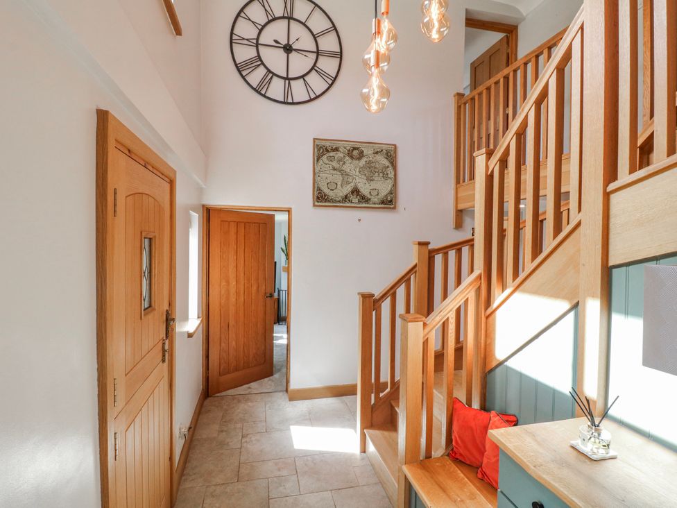 A hallway with a staircase and clock at Brecks Cottage Moorhouse near Tuxford