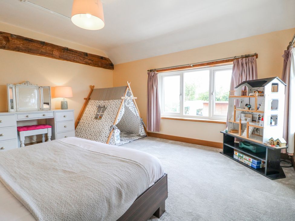 A bedroom with a bed, mirror, lamp, tent and dollhouse at Brecks Cottage near Moorhouse Tuxford