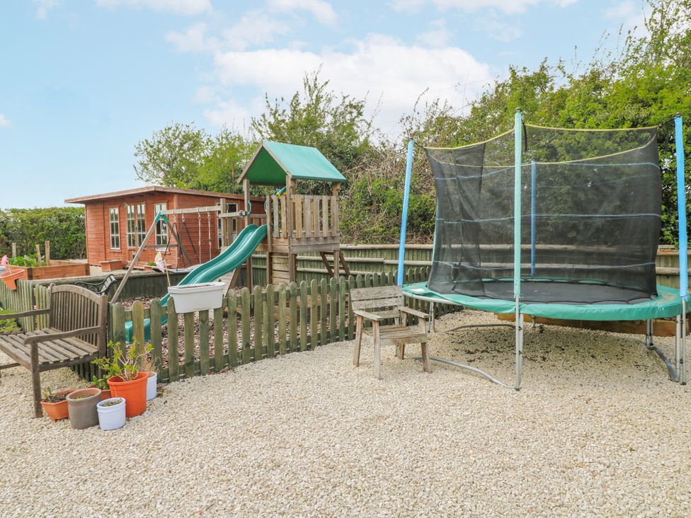 A garden with a playhouse, slide, trampoline and seating area at Brecks Cottage in Moorhouse near Tuxford