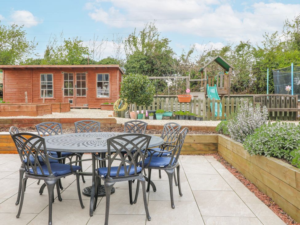 A garden with a table and chairs near a playhouse at Brecks Cottage Moorhouse near Tuxford