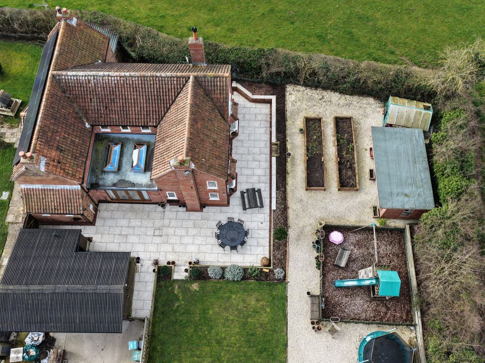An outdoor area with a house, patio, garden beds and a playhouse at Brecks Cottage near Tuxford