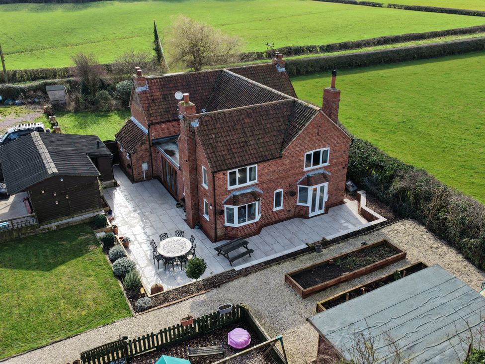 An outdoor view of a house with a patio and garden at Brecks Cottage Moorhouse near Tuxford