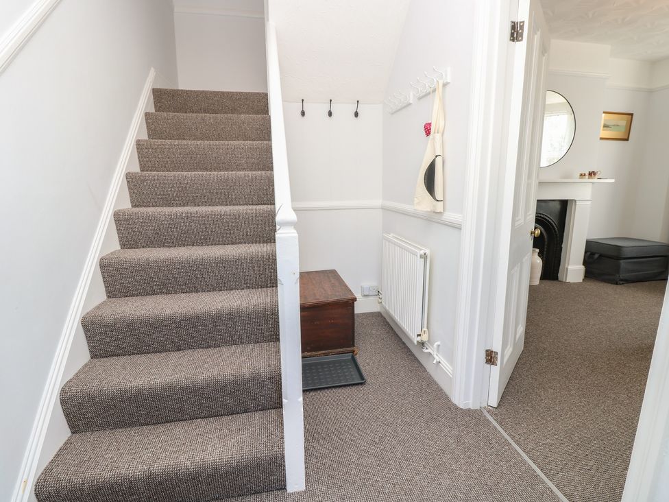 A hallway with stairs, a radiator, and a mirror at Bay Tree Cottage in Shanklin
