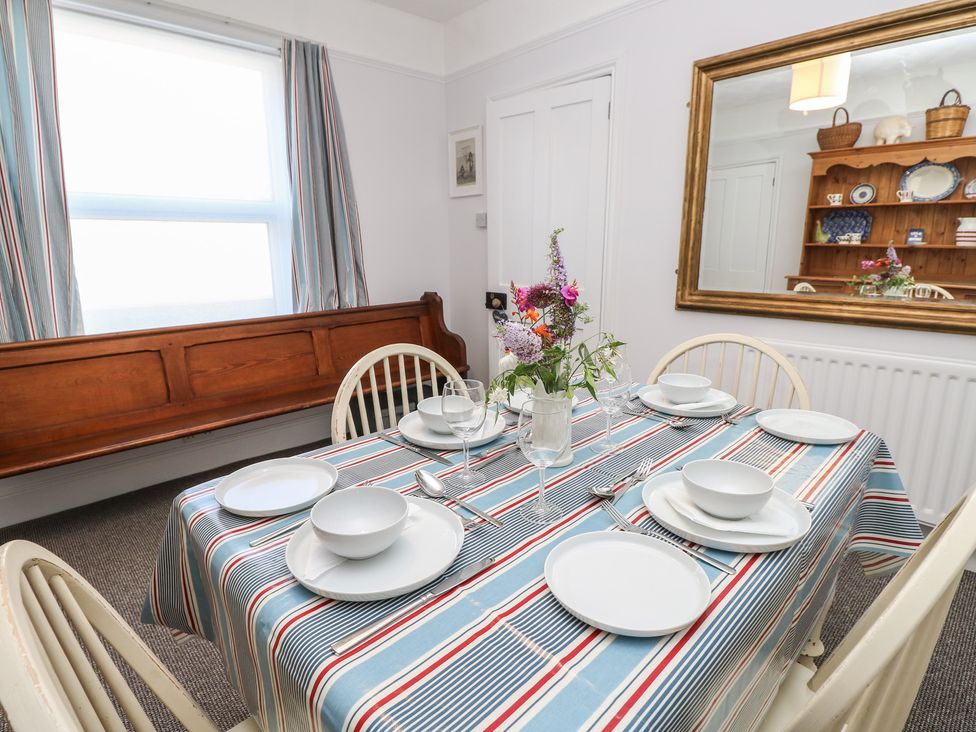 A dining room with a table set for several people at Bay Tree Cottage in Shanklin