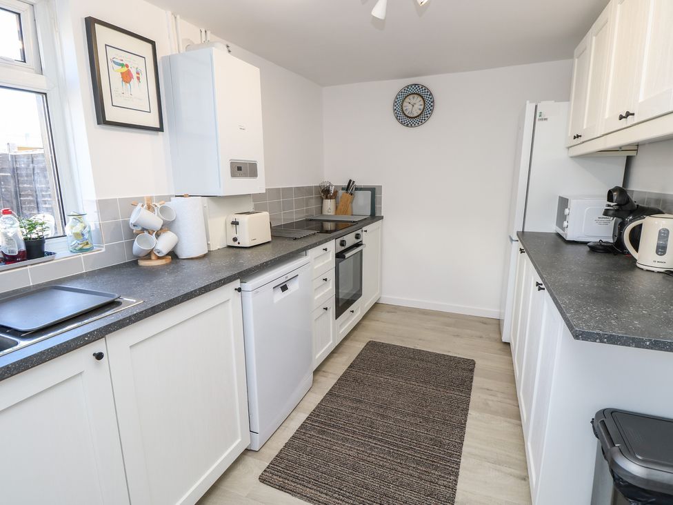 A kitchen with appliances and a rug at Bay Tree Cottage in Shanklin