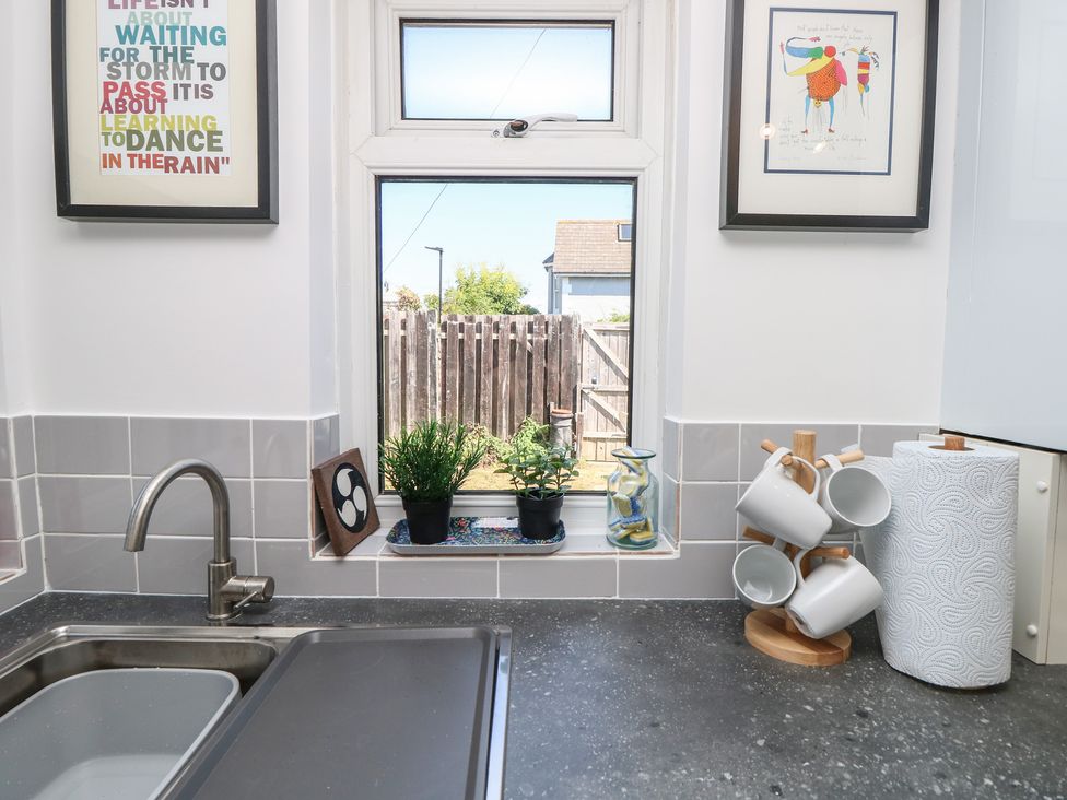 A kitchen sink with a window and houseplants at Bay Tree Cottage in Shanklin