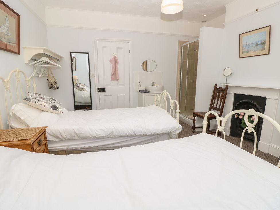 A bedroom with two beds and a mirror at Bay Tree Cottage in Shanklin