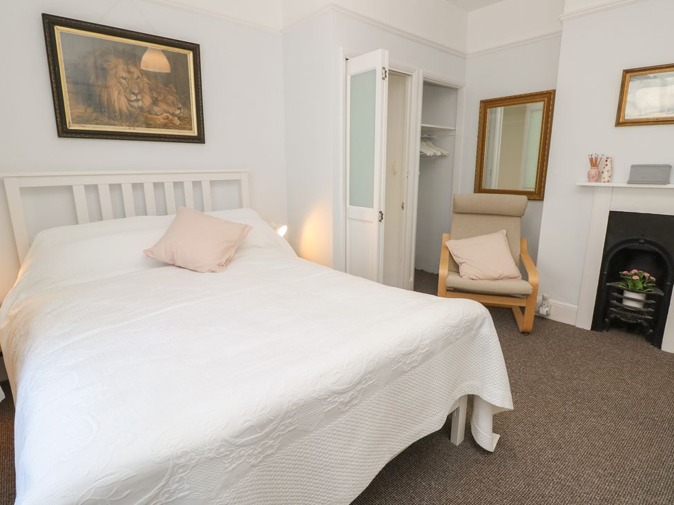A bedroom with a bed and chair at Bay Tree Cottage in Shanklin