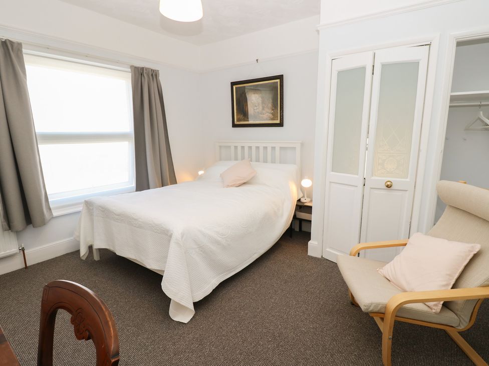 A bedroom with a bed and armchair at Bay Tree Cottage in Shanklin