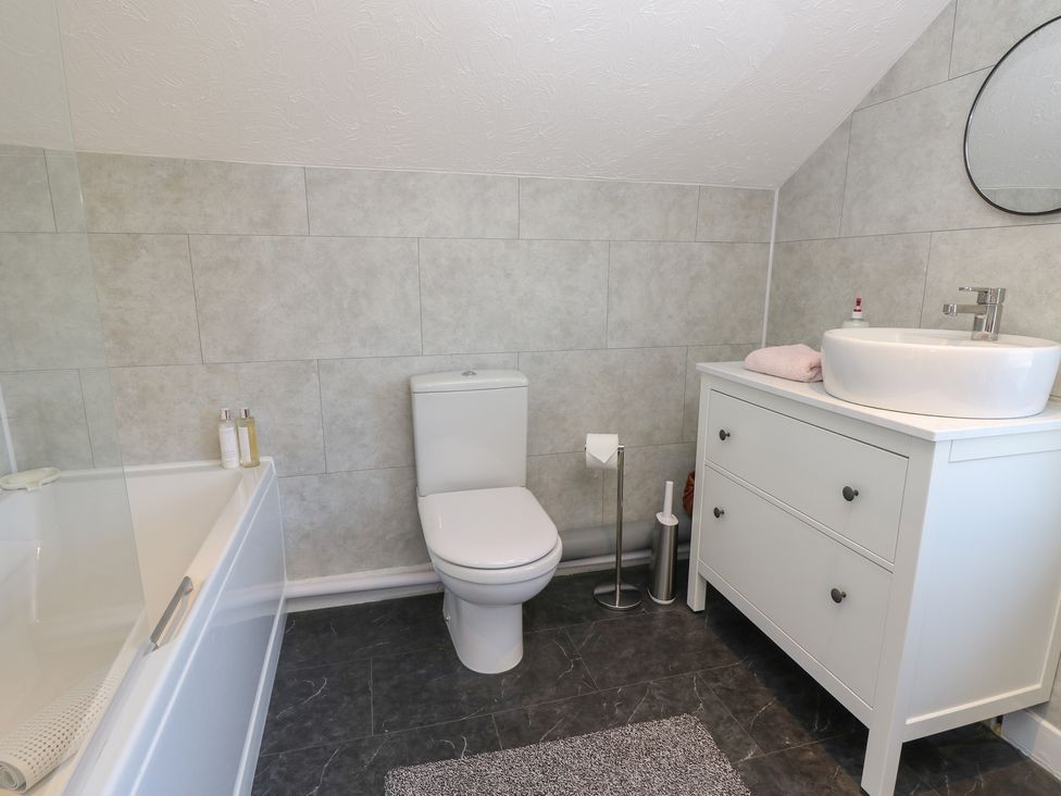 A bathroom with a bathtub, toilet, and sink at Bay Tree Cottage in Shanklin