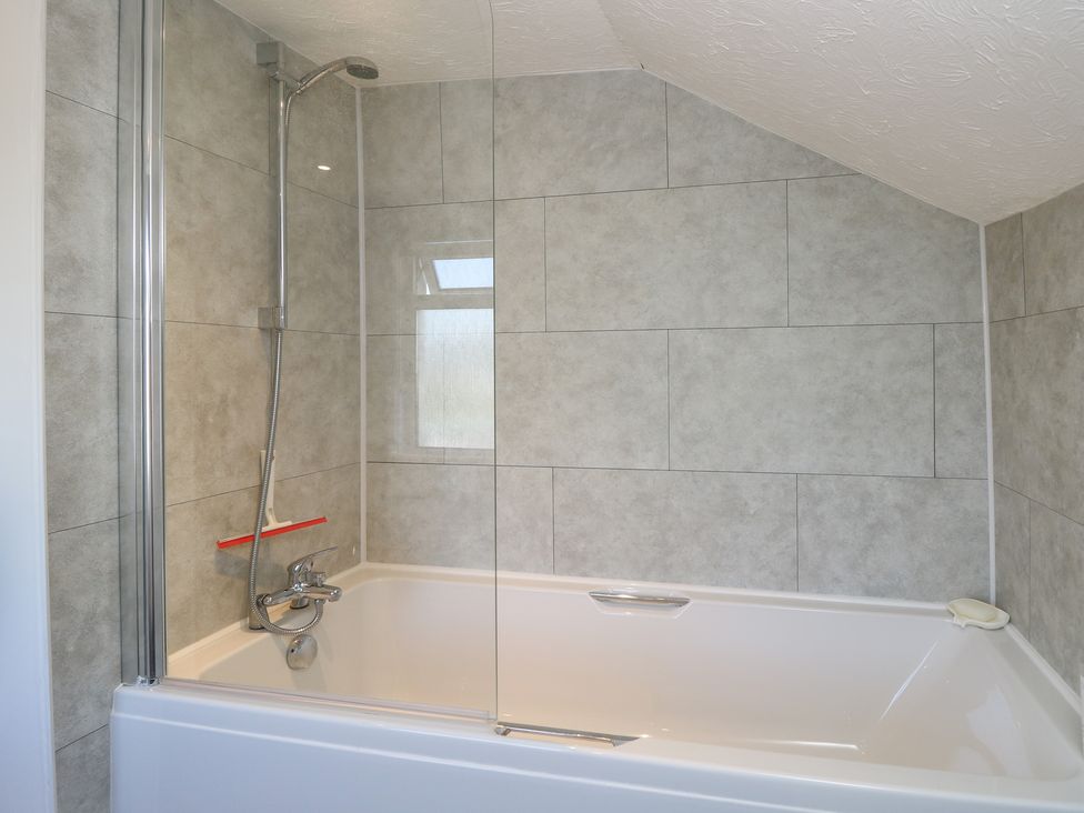 A bathroom with a bathtub and shower at Bay Tree Cottage in Shanklin