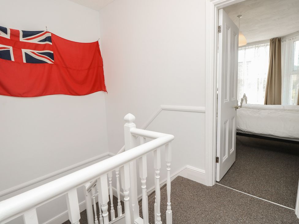 A hallway with a flag on the wall and a door leading to a bedroom at Bay Tree Cottage in Shanklin